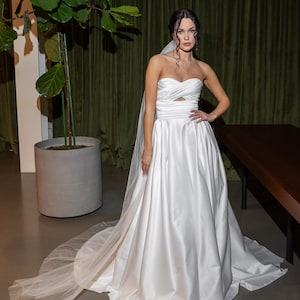 Robe de mariée drapée en satin avec les luxueuses jupes en satin.