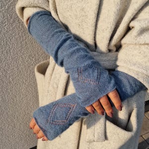 May include: A pair of blue knitted arm warmers with a geometric pattern. The arm warmers are made of a soft, fuzzy material and are perfect for keeping your arms warm in the winter.