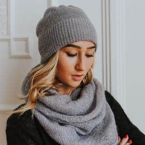 Peut inclure: Un bonnet et une &eacute;charpe en tricot gris assortis. Le bonnet est c&ocirc;tel&eacute; et l'&eacute;charpe est en tricot l&acirc;che.