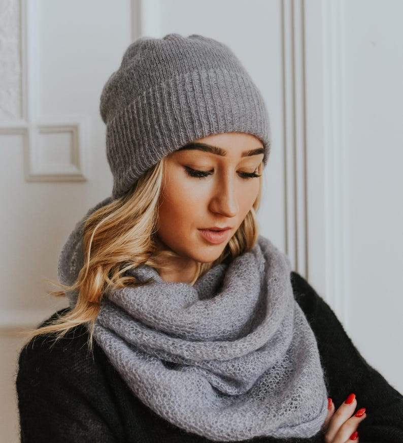 Peut inclure: Un bonnet et une &eacute;charpe en tricot gris assortis. Le bonnet est c&ocirc;tel&eacute; et l'&eacute;charpe est en tricot l&acirc;che.