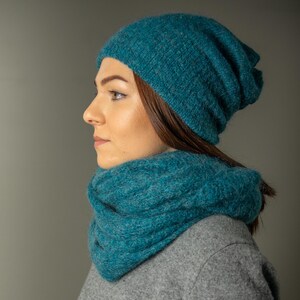 Peut inclure: Un bonnet et une &eacute;charpe infinie assortis en tricot bleu sarcelle. Le bonnet est ample et l'&eacute;charpe est &eacute;paisse et confortable.