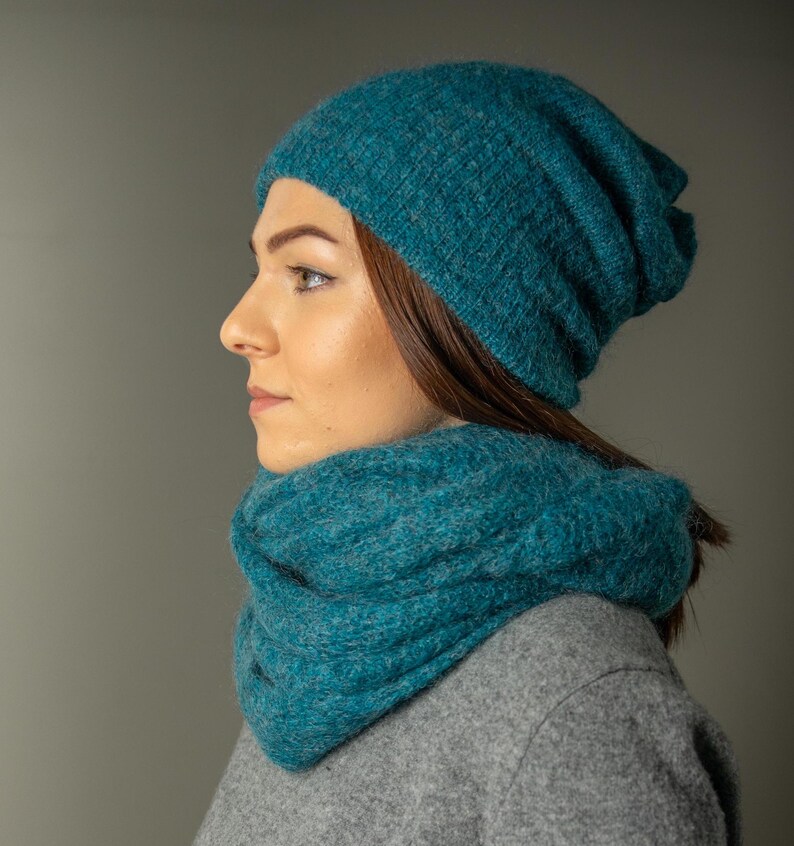 Peut inclure: Un bonnet et une &eacute;charpe infinie assortis en tricot bleu sarcelle. Le bonnet est ample et l'&eacute;charpe est &eacute;paisse et confortable.