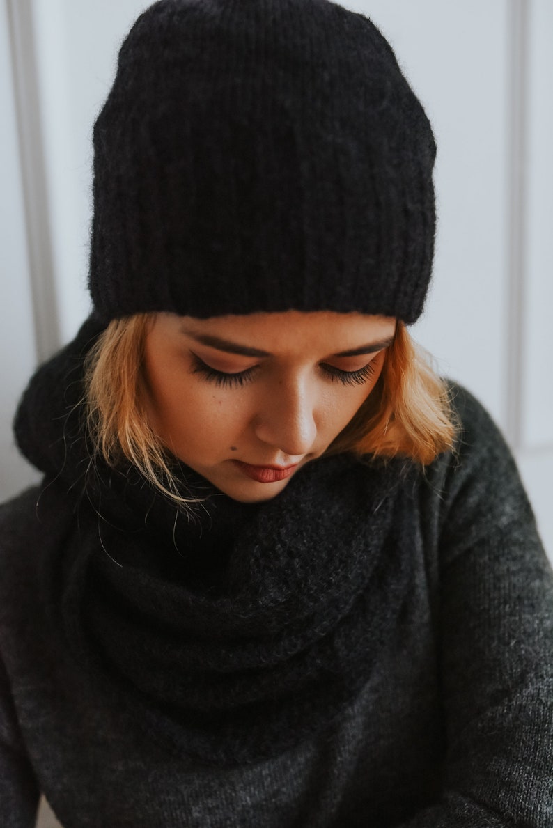 Peut inclure: Une femme portant un bonnet noir en tricot et une &eacute;charpe noire. Elle regarde vers le bas et ses cheveux sont blonds.