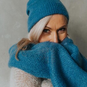 Peut inclure: Une femme portant un bonnet en tricot bleu sarcelle et une &eacute;charpe assortie. Elle porte un pull cr&egrave;me.