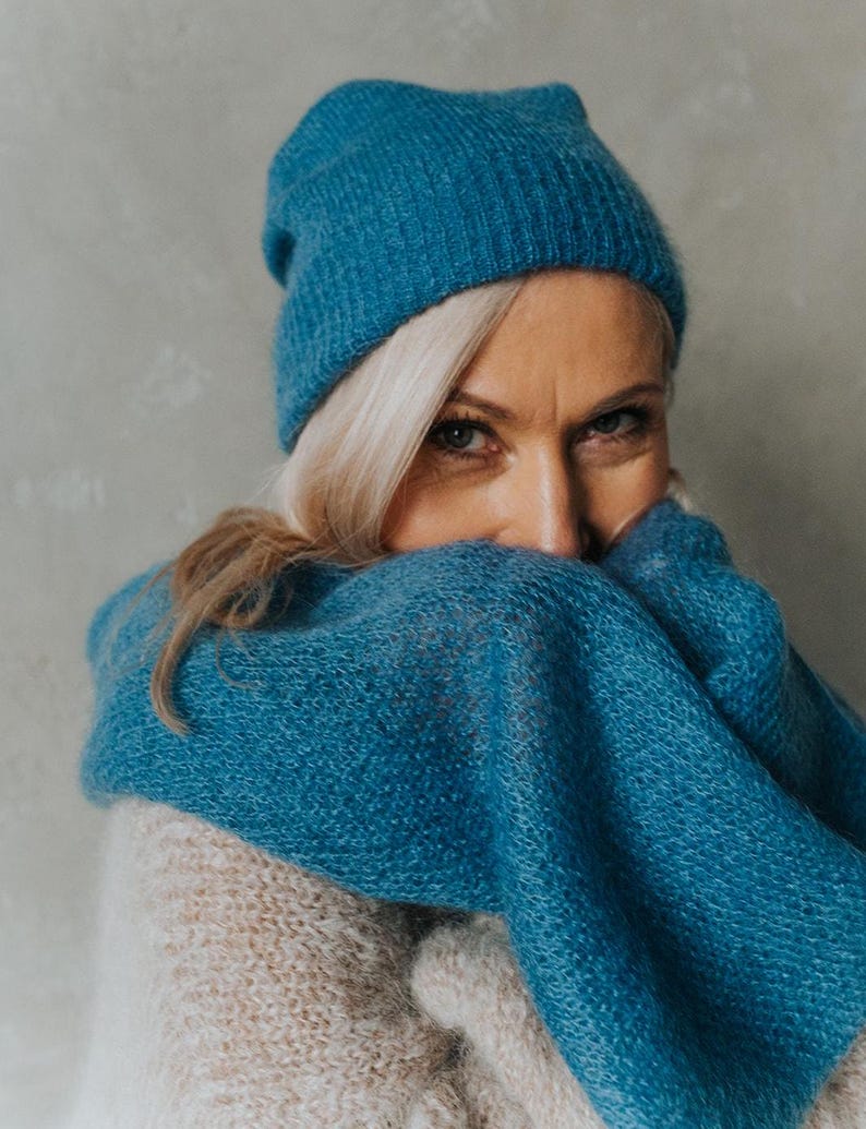 Peut inclure: Une femme portant un bonnet en tricot bleu sarcelle et une &eacute;charpe assortie. Elle porte un pull cr&egrave;me.