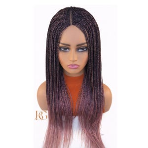 May include: A braided wig with a dark brown to pink ombre effect. The wig features a centre parting and long, straight braids. The wig is displayed on a mannequin head with an orange top.