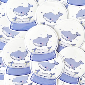 Pode incluir: Uma cole&ccedil;&atilde;o de adesivos de bola de neve de baleia azul e branca. Cada adesivo apresenta uma baleia de desenho animado nadando dentro de uma bola de neve com uma base azul.