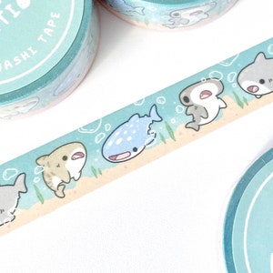 A row of cute shark illustrations printed on a roll of washi tape. Shark species including: hammerheads, great whites, tiger sharks, and whale sharks