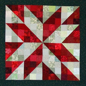 May include: A red and green patchwork quilt with a starburst design. The quilt is made of various fabrics with different patterns and textures.