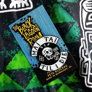 May include: Black and white enamel pin with a skull drinking a cocktail. The pin says "Mai Tai Til I Die" with the text "Fun Pete Klockau Made in Milwaukee, WI".