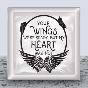 May include: A white square with a black circle and wings. The circle has the text "Your wings were ready, but my heart was not".