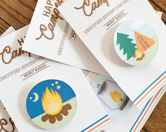 May include: Four white cards with the text "Happy Camper" and "Certified Adventure Seeker" with a merit badge graphic. Each card has a different badge design: a campfire, a lantern, a tent, and a pine tree.