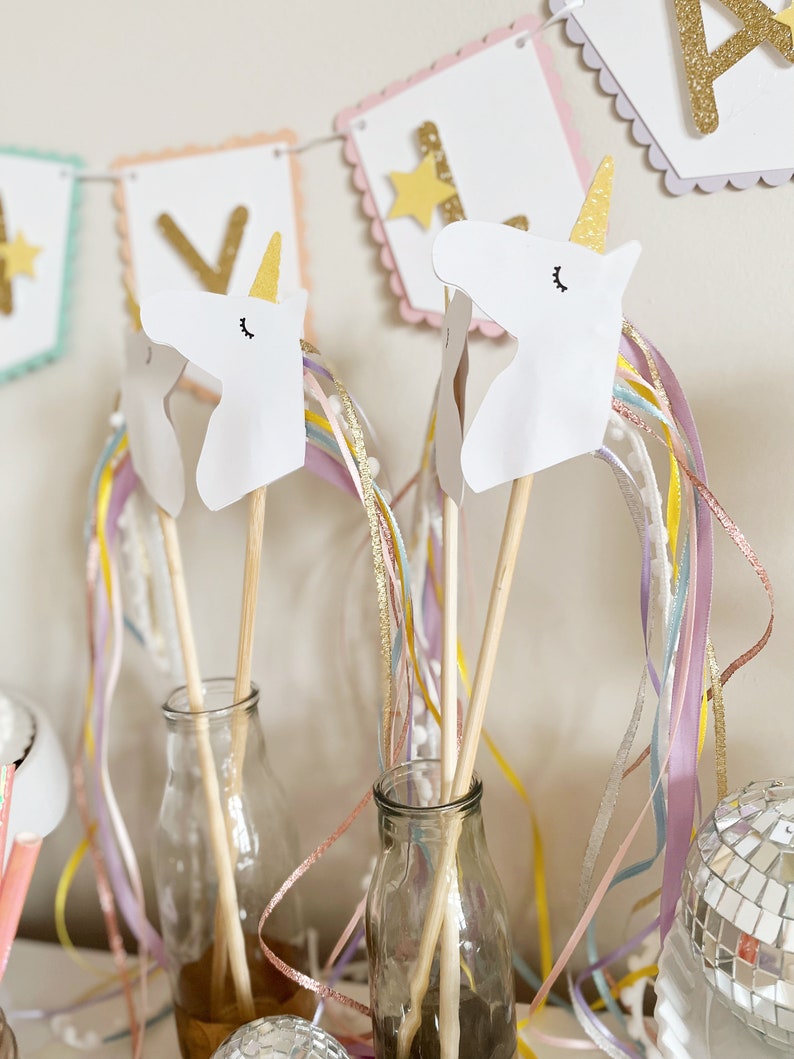 Pu&ograve; includere: Due bacchette a forma di testa di unicorno bianca con corna dorate e nastri arcobaleno in bottiglie di vetro. Le teste di unicorno sono fatte di carta e hanno occhi e ciglia neri. Le bacchette sono fatte di legno e sono lunghe circa 30 cm. I nastri sono fatti di nastro colorato e sono lunghi circa 45 cm.