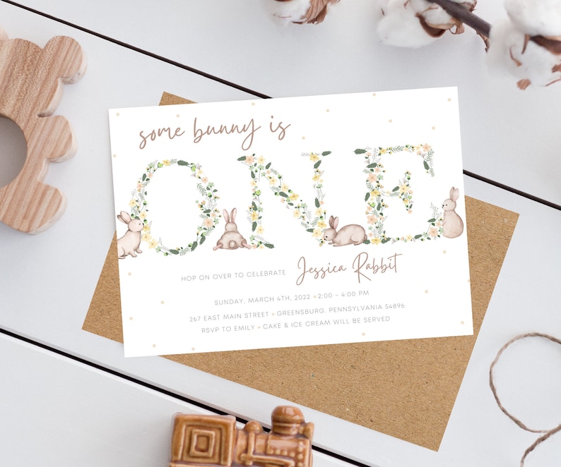 May include: A white invitation card with a floral wreath spelling out "ONE" with a bunny rabbit in each letter. The text "some bunny is" is above the wreath and the text "Jessica Rabbit" is below the wreath. The invitation details a first birthday party with the date, time, location, and RSVP information.
