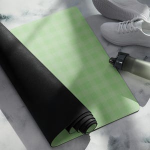 May include: A rolled-up black yoga mat next to a light green yoga mat with a textured pattern. White athletic shoes and a gray water bottle are also in the image. The items suggest a fitness or wellness theme.