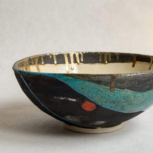 Puede incluir: Una taza de cerámica blanca con un asa negra y el texto "But First, Coffee" en negrita negra. La taza se encuentra sobre un fondo neutro, resaltando su diseño sencillo.