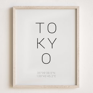 May include: A framed print with the word "TOKYO" in black text and the coordinates "35°39'38.5"N 139°45'45.2"E" in smaller text below.