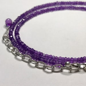 May include: A delicate purple amethyst necklace with a silver chain and clasp. The necklace is made of small, faceted amethyst beads.