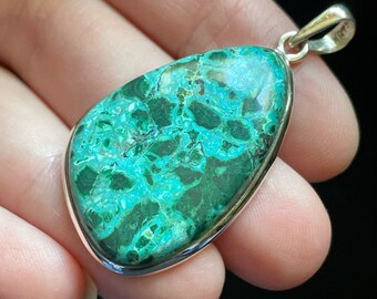 May include: A green and blue gemstone pendant with a silver setting. The pendant is in the shape of a teardrop and has a mottled pattern.