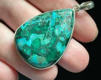 May include: A teardrop-shaped pendant with a green and blue chrysocolla stone set in silver.
