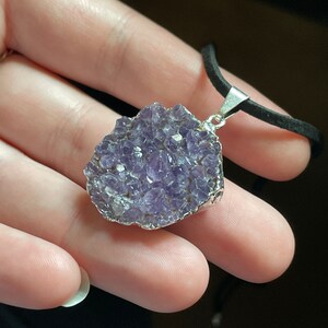 May include: A silver necklace with a purple amethyst pendant. The pendant is a cluster of small amethyst crystals.