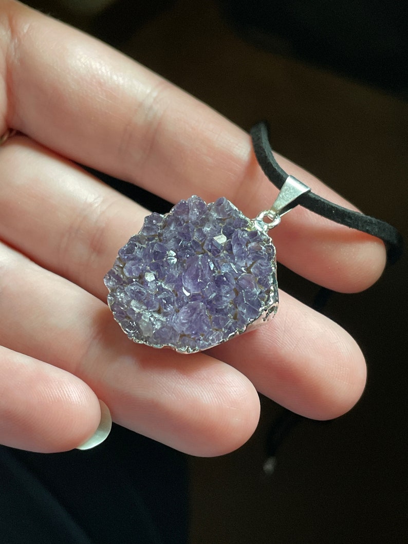 May include: A silver necklace with a purple amethyst pendant. The pendant is a cluster of small amethyst crystals.