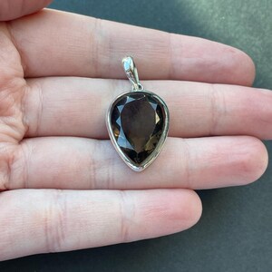 May include: A silver pendant with a teardrop-shaped smoky quartz gemstone.