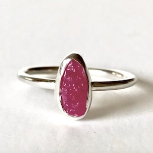 May include: A silver ring with a pink oval-shaped gemstone set in the center.