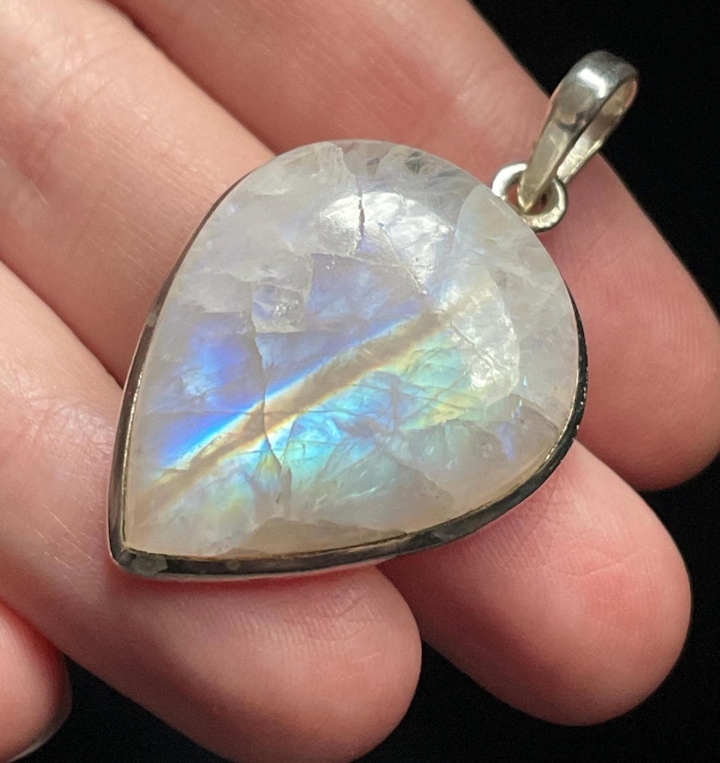 May include: A teardrop-shaped moonstone pendant with a silver setting. The moonstone has a rainbow sheen and is set in a silver bezel.