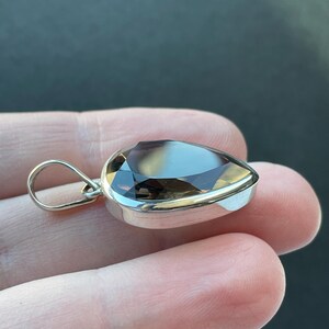 May include: A silver pendant with a teardrop-shaped smoky quartz gemstone.
