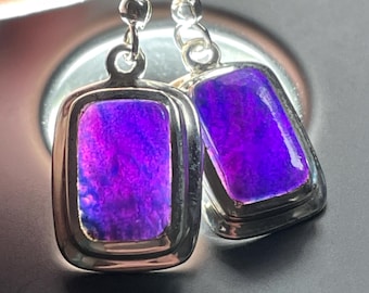 May include: A pair of silver earrings with purple gemstone rectangular drops. The earrings have a simple design and are perfect for everyday wear.