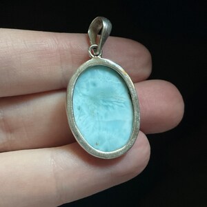 Puede incluir: Un colgante de plata con una piedra ovalada de color azul claro. El colgante tiene un dise&ntilde;o sencillo y es perfecto para a&ntilde;adir un toque de elegancia a cualquier atuendo.