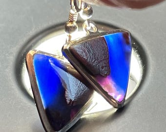 May include: A pair of silver triangle earrings with iridescent blue and purple glass inserts.
