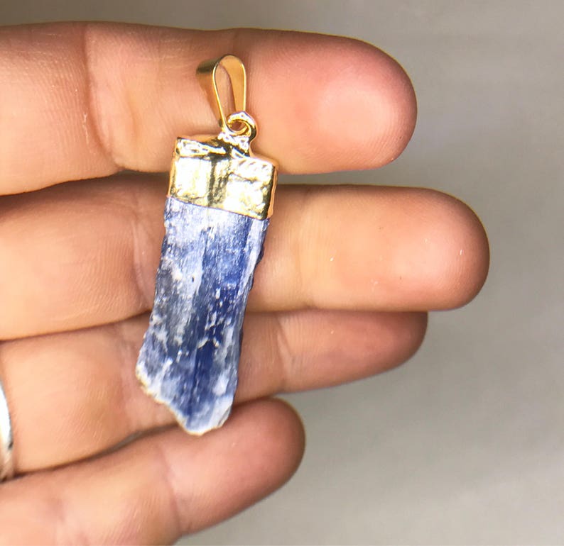 May include: A blue kyanite crystal pendant with a gold-plated bail. The crystal is raw and has a natural, irregular shape.