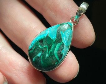 May include: A teardrop-shaped pendant with a green and black malachite stone set in silver.