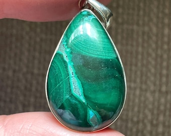 May include: A teardrop-shaped pendant with a green malachite stone set in silver.