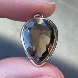 May include: A teardrop-shaped pendant with a large, faceted smoky quartz gemstone set in sterling silver.