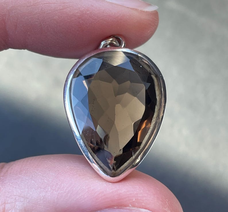 May include: A teardrop-shaped pendant with a large, faceted smoky quartz gemstone set in sterling silver.