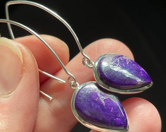 May include: A pair of silver dangle earrings with purple and white gemstone drops.
