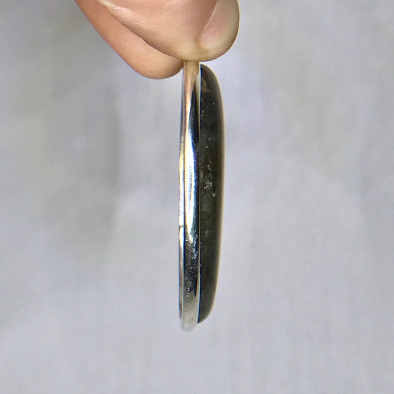May include: A silver pendant with a black oval gemstone.
