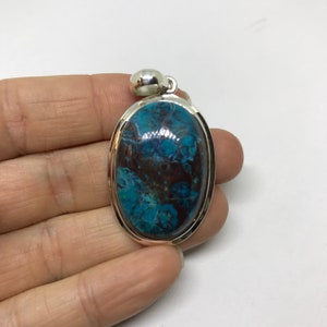 Peut inclure: Pendentif de forme ovale avec une pierre pr&eacute;cieuse bleue et brune sertie dans un cadre argent&eacute;.