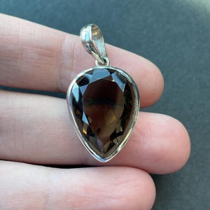 May include: A silver pendant with a teardrop-shaped smoky quartz gemstone.