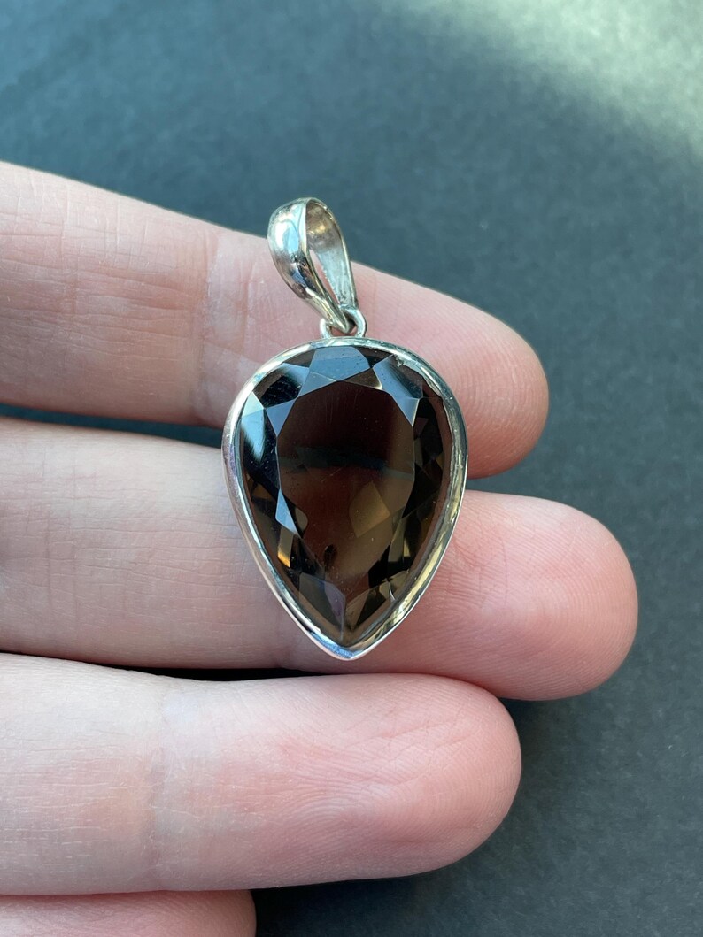 May include: A silver pendant with a teardrop-shaped smoky quartz gemstone.