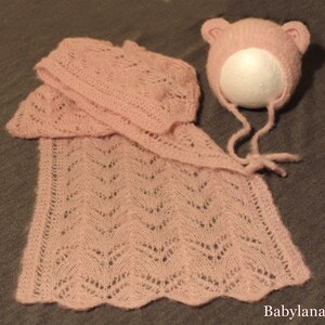 Puede incluir: Un gorro y una chalina de punto rosa para bebé con un delicado patrón de encaje.