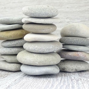 Puede incluir: Una pila de piedras lisas, grises y marrones, equilibradas unas sobre otras. Las piedras están dispuestas en forma de pirámide, con la piedra más grande en la parte inferior y la más pequeña en la parte superior.