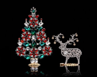 May include: A jeweled Christmas tree ornament with red, green, and clear rhinestones. A jeweled reindeer ornament with clear rhinestones is next to the tree.