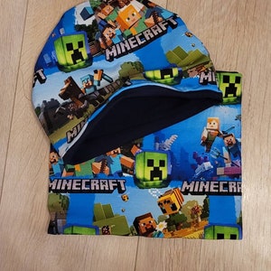 May include: A blue and green Minecraft-themed beanie hat with a navy blue fleece lining. The hat features a repeating pattern of Minecraft characters and the word "Minecraft".
