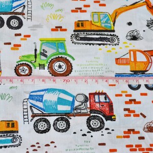 May include: A white fabric with a repeating pattern of colorful construction vehicles. The vehicles include a cement mixer, a tractor, an excavator, and a crane. The fabric also features brick patterns and green grass.
