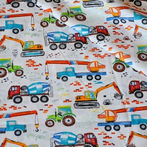 May include: White fabric with a repeating pattern of colorful construction vehicles. The vehicles include a crane, a cement mixer, an excavator, and a tractor. The fabric is perfect for crafting projects, quilting, and sewing.