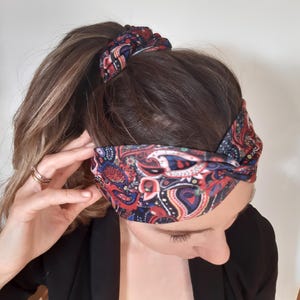Puede incluir: Una diadema con estampado paisley rojo, azul y blanco con un diseño de nudo retorcido.